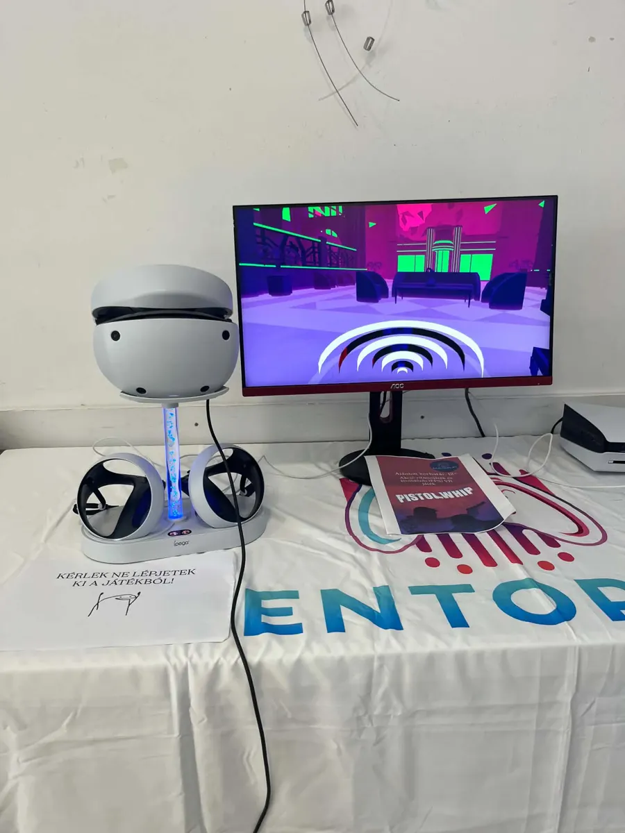 PlayStation VR2 headset állványon, mögötte monitor, RenToPlay-terítővel letakart asztal